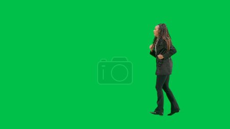 Photo for Tv news and live broadcasting concept. Young female reporter isolated on chroma key green screen background. Full shot african american woman tv news host running. Side view. - Royalty Free Image