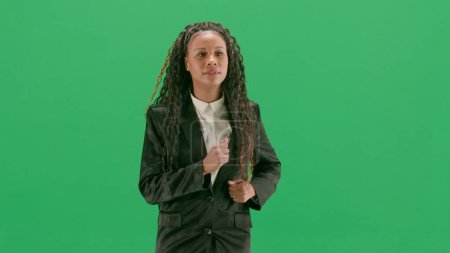 Photo for Tv news and live broadcasting concept. Young female reporter isolated on chroma key green screen background. African american woman tv news host running. - Royalty Free Image
