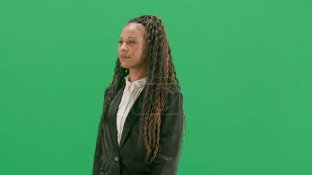 Nouvelles TV et concept de diffusion en direct. Jeune reporter femelle isolée sur fond vert chromatique. African american woman tv news host walking. Demi-tour.