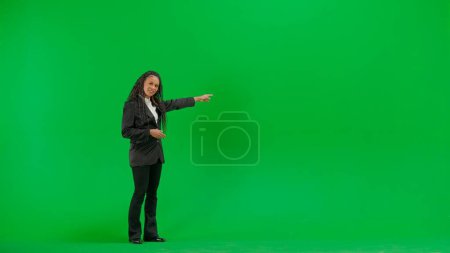Photo for Tv news and live broadcasting concept. Young female reporter isolated on chroma key green screen background. Full shot african american woman tv news host talking smiling at camera. - Royalty Free Image