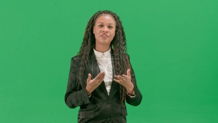 Tv news and live broadcasting concept. Young female reporter isolated on chroma key green screen background. African american woman tv news host anchor talking looking at camera.
