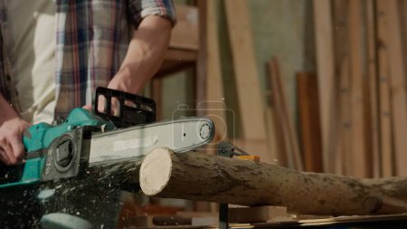 Photo for Carpentry and handicraft advertisement concept. Male woodworker working in garage. Man professional carpenter working with wooden materials in workshop sawing wood using electric chainsaw. - Royalty Free Image