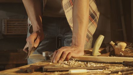 Foto de Concepto de publicidad de carpintería y artesanía. Hombre carpintero trabajando en garaje. Hombre carpintero profesional trabajando con materiales de madera en taller y lijado panel de madera con papel de lija. - Imagen libre de derechos