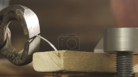 Carpentry and handicraft advertisement concept. Male woodworker working in garage. Man professional carpenter working in workshop, close up shot of wooden plank with nail removed by a nail puller.
