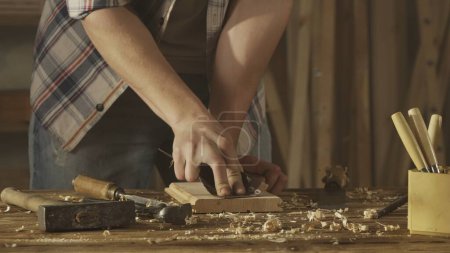 Photo for Carpentry and handicraft advertisement concept. Male woodworker working in garage. Man professional carpenter working with wooden materials in workshop and sanding wooden panel with sandpaper. - Royalty Free Image