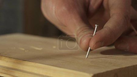 Photo for Carpentry and handicraft advertisement concept. Male woodworker working in garage. Man professional carpenter working with wooden materials in workshop and hitting nail in wooden panel, close up. - Royalty Free Image