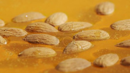 Photo for Food advertisement concept. Healthy organic honey. Sweet fresh golden honey on the yellow background, almond nuts in the thick syrup, close up shot. - Royalty Free Image