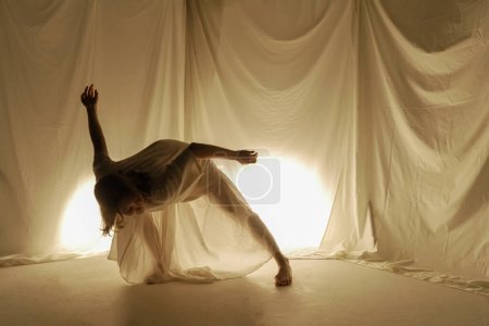 A dancer bends artistically, backlit by a warm glow, creating a dynamic silhouette