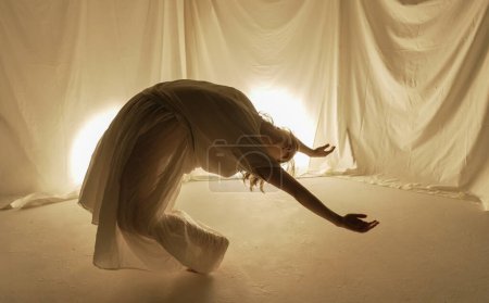 Photo for A dancers silhouette against a luminous backdrop, captured in mid-motion with flowing fabrics. - Royalty Free Image