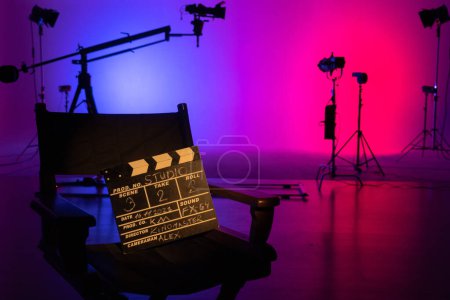Téléchargez les photos : La silhouette emblématique d'une chaise de réalisateur se distingue dans un studio de cinéma très éclairé, évoquant le pouls créatif de la réalisation cinématographique. Coulisses. - en image libre de droit