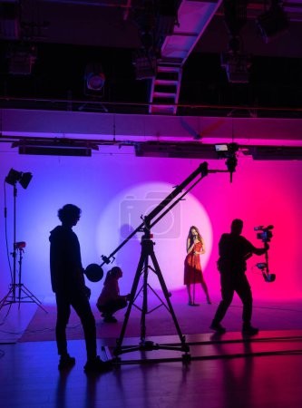 Téléchargez les photos : Film dynamique avec une silhouette vibrante de l'équipe et de l'actrice sur fond coloré. Coulisses. - en image libre de droit