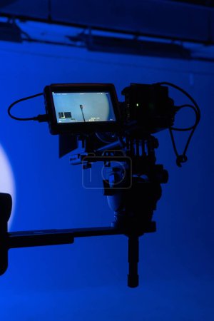 Téléchargez les photos : Une silhouette de caméras avec un fond bleu néon frappant, une métaphore visuelle pour la production cinématographique moderne. - en image libre de droit
