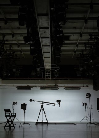 Silhouette of film set equipment with directors chair casting long shadows in a studio, encapsulating the quiet anticipation of a shoot