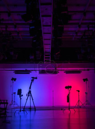 Téléchargez les photos : Studio de production de films en silhouette sur fond rose néon vibrant avec un équipement d'éclairage professionnel. Coulisses. - en image libre de droit