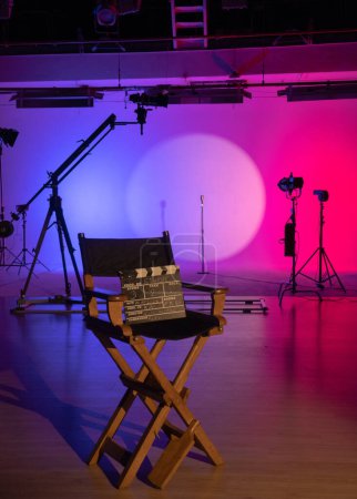 Téléchargez les photos : La silhouette emblématique d'une chaise de réalisateur se distingue dans un studio de cinéma très éclairé, évoquant le pouls créatif de la réalisation cinématographique. Coulisses. - en image libre de droit