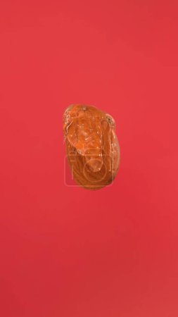Photo for Thin trickle of amber honey pours and covers almond nut on red background. A close-up of a nut watered with sweet pulling honey. The concept of healthy tasty food. - Royalty Free Image