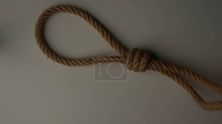 Marine or safety sport knots tying process. Old thick rope twisted and tied up creating knot, isolated on white background, close up shot. Rope tied in a knot, top view falling on surface.