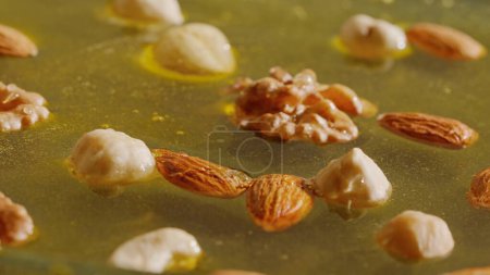 Téléchargez les photos : Miel bio sain aux noix. Miel d'or frais sucré aux amandes, noix et noisettes dans le sirop épais, gros plan. - en image libre de droit