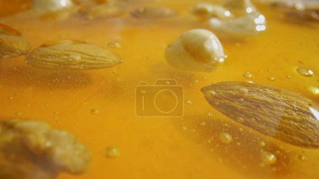 Foto de Miel orgánica saludable con nueces. Dulce miel dorada fresca con almendras, nueces y avellanas en el jarabe grueso, primer plano. - Imagen libre de derechos