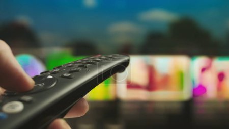 Photo for Female hand holding remote. Woman with remote in hand switching channels, smart tv technology internet video content, screen with content at the background close up shot. - Royalty Free Image