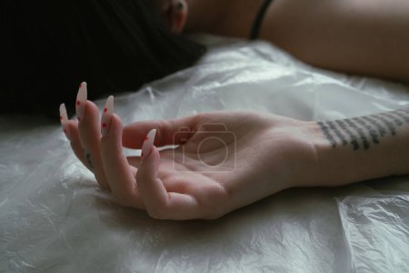 Téléchargez les photos : Un gros plan d'une femme mains élégantes avec une manucure unique motif coeur, reposant sur un drap de lit blanc, complété par des tatouages visibles de l'avant-bras - en image libre de droit