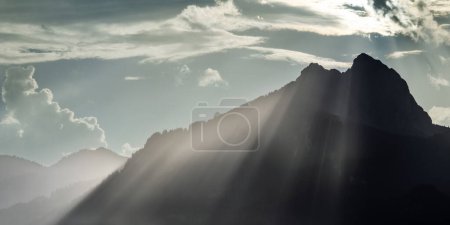 Photo for Voluminous grazing light beams over the crest of the hahnenkamm mountains at sunset after a thunderstorm - Royalty Free Image
