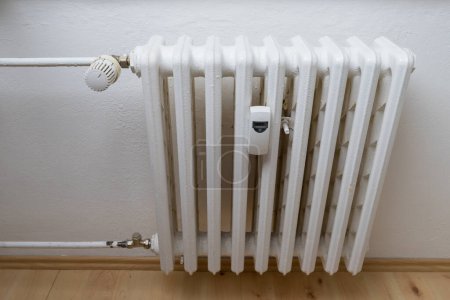 Radiador de calefacción con medidor de calor y válvula para regulación.