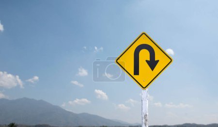 Photo for Traffic sign: Right U-turn sign on cement pole beside the rural road with white cloudy bluesky background, copy space. - Royalty Free Image