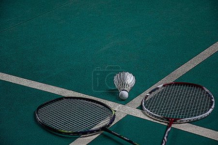 Foto de El jugador de bádminton sostiene la raqueta y el volante de crema blanca frente a la red antes de servirlo en otro lado de la cancha. - Imagen libre de derechos