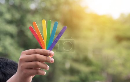 Photo for Ice-cream sticks in rainbow colours holding in hands of asian boy, soft and selective focus, concept for calling out all people to support LGBT events and campaigns around the world. - Royalty Free Image