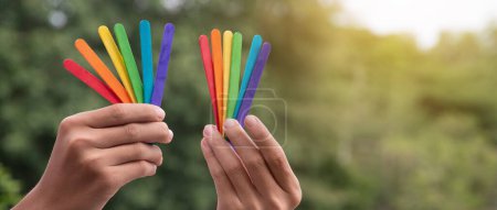 Photo for Ice-cream sticks in rainbow colours holding in hands of asian boy, soft and selective focus, concept for calling out all people to support LGBT events and campaigns around the world. - Royalty Free Image