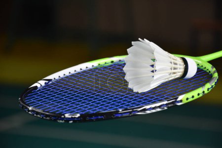 Photo for Badminton player is holding white badminton shuttlecock and badminton racket in front of the net before serving it over the net to another side of badminton court. Selective focus on white shuttlecock - Royalty Free Image
