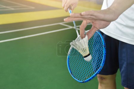 Téléchargez les photos : Joueur de badminton tient raquette et crème blanche navette devant le filet avant de le servir à un autre côté du terrain, concept de service célibataire. - en image libre de droit