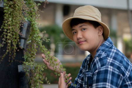 Asiatischer süßer Junge mit dem Nest der Nickelpflanze, das er im eigenen Vorgarten am Baumstamm aufgehängt hat, weich und selektiv.