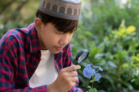 Asiatischer netter Schuljunge hält ein tragbares Mini-Mikroskop in der Hand und betrachtet die kleinen Details der Topfpflanze zum Lernen und Entspannen durch die Linse, selektiver Fokus auf