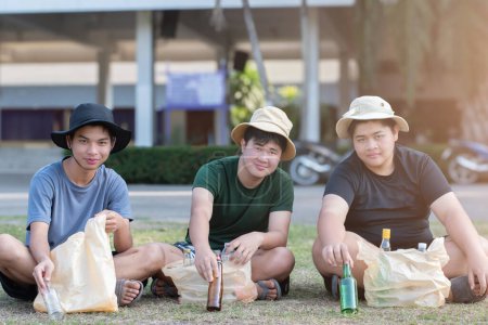 Téléchargez les photos : Les volontaires garçons asiatiques collectent des bouteilles en verre et en plastique dans le parc scolaire, les soins de l'environnement, les services communautaires et les activités de vacances d'été des adolescents concept, soft focus. - en image libre de droit