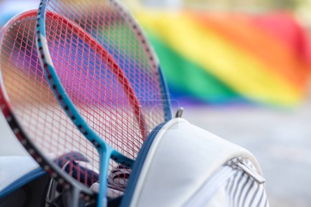 Photo for Badminton sport equipments, rackets and sportbag placed on floor with blurred rainbow flag background, concept for popular sports with all gender and lgbt people around the world. - Royalty Free Image