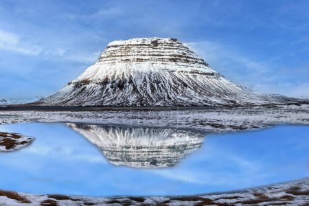 Der Vulkan Kirkjufell im Winter spiegelt sich in einem See wider. Island
