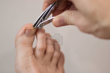 Téléchargez les photos : Couper un ongle sur un gros orteil sur un pied droit sur un fond blanc. - en image libre de droit