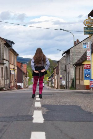 Téléchargez les photos : Lohnsfeld, Allemagne - Mai 16, 2021 : Adolescente portant des collants roses et noirs debout au milieu de la rue principale à Lohnsfeld, Allemagne. - en image libre de droit