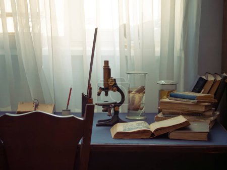 Foto de Oficina retro de un antiguo científico. microscopio anticuado, pila de libros y botellas en la mesa de escritorio, frascos con animales muertos alcoholizados - Imagen libre de derechos