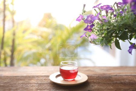 Foto de Zumo de rosela y flor de petunia en mesa de madera - Imagen libre de derechos