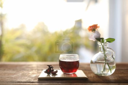 Foto de Rosella Jugo en una taza de vidrio en bandeja de madera y flor de rosa en un jarrón de vidrio - Imagen libre de derechos
