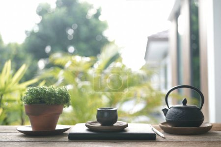 Téléchargez les photos : Tasse à thé et théière en métal et pot de plante sur table en bois boisson relaxante extérieure - en image libre de droit
