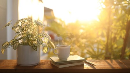 Kaffeetasse und Notizbuch und Engelsflügel auf Holztisch im Sonnenlicht