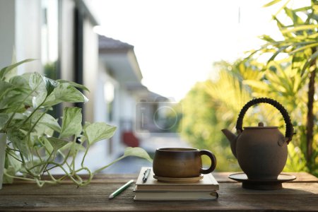 Tea cup and earthenware teapot at the balcony and Laptop side view