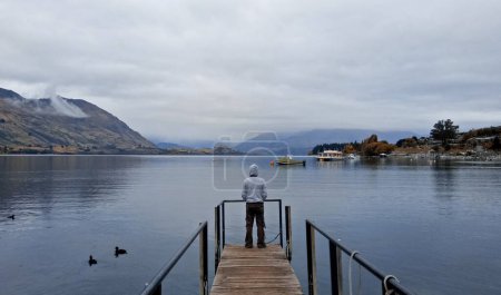Photo for A man standing at the dock in Lake Wanaka, New Zealand. - Royalty Free Image