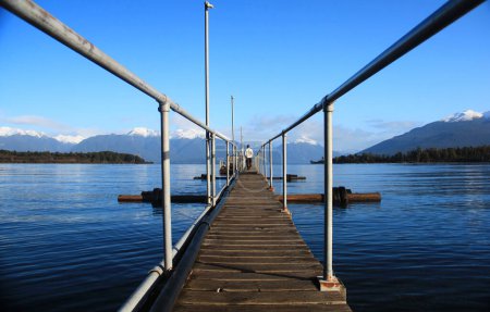 Photo for A woman walks on the bridge of a pier on the shore of lake Te Anau. - Royalty Free Image