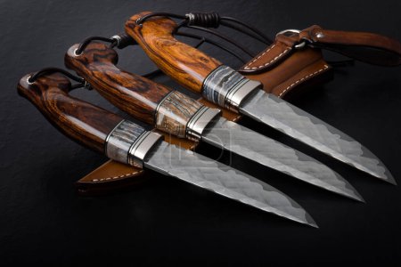 Foto de Tres cuchillos de caza hechos a mano sobre un fondo negro. - Imagen libre de derechos