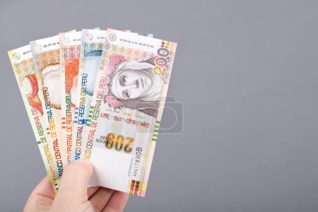 Foto de Peruvian money - Soles in the hand on a gray background - Imagen libre de derechos